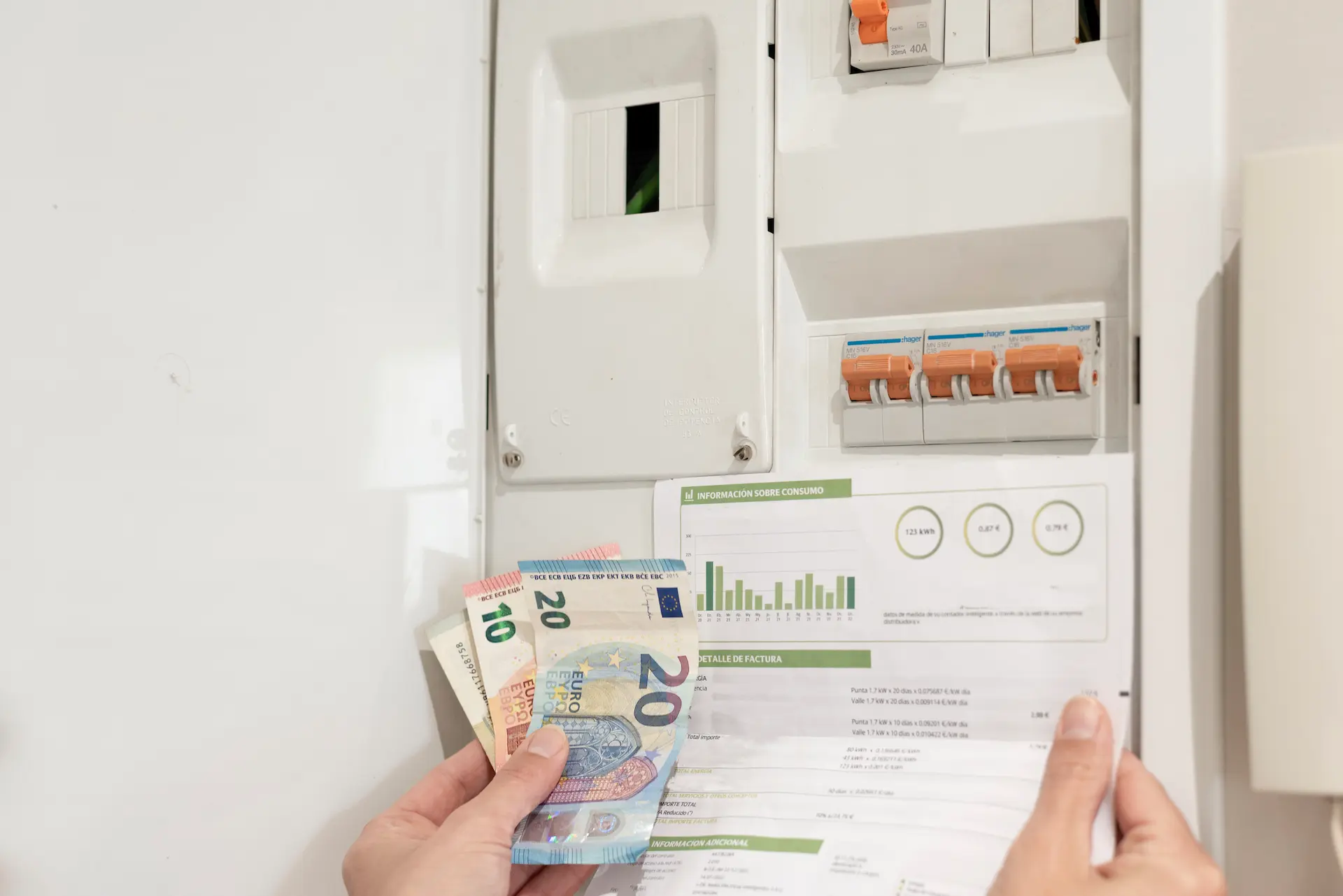 Electricity bill with euro banknotes in front of an open fuse box.