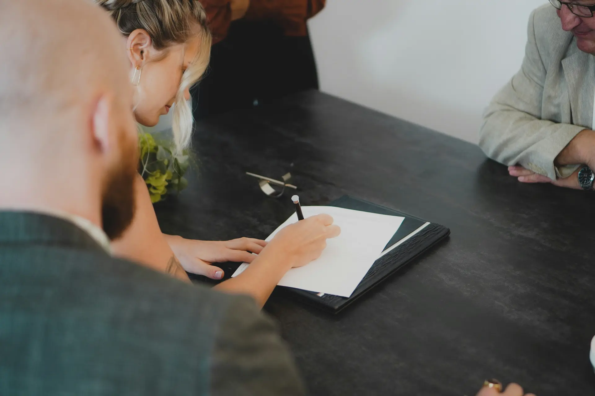 A person signs a document at a table