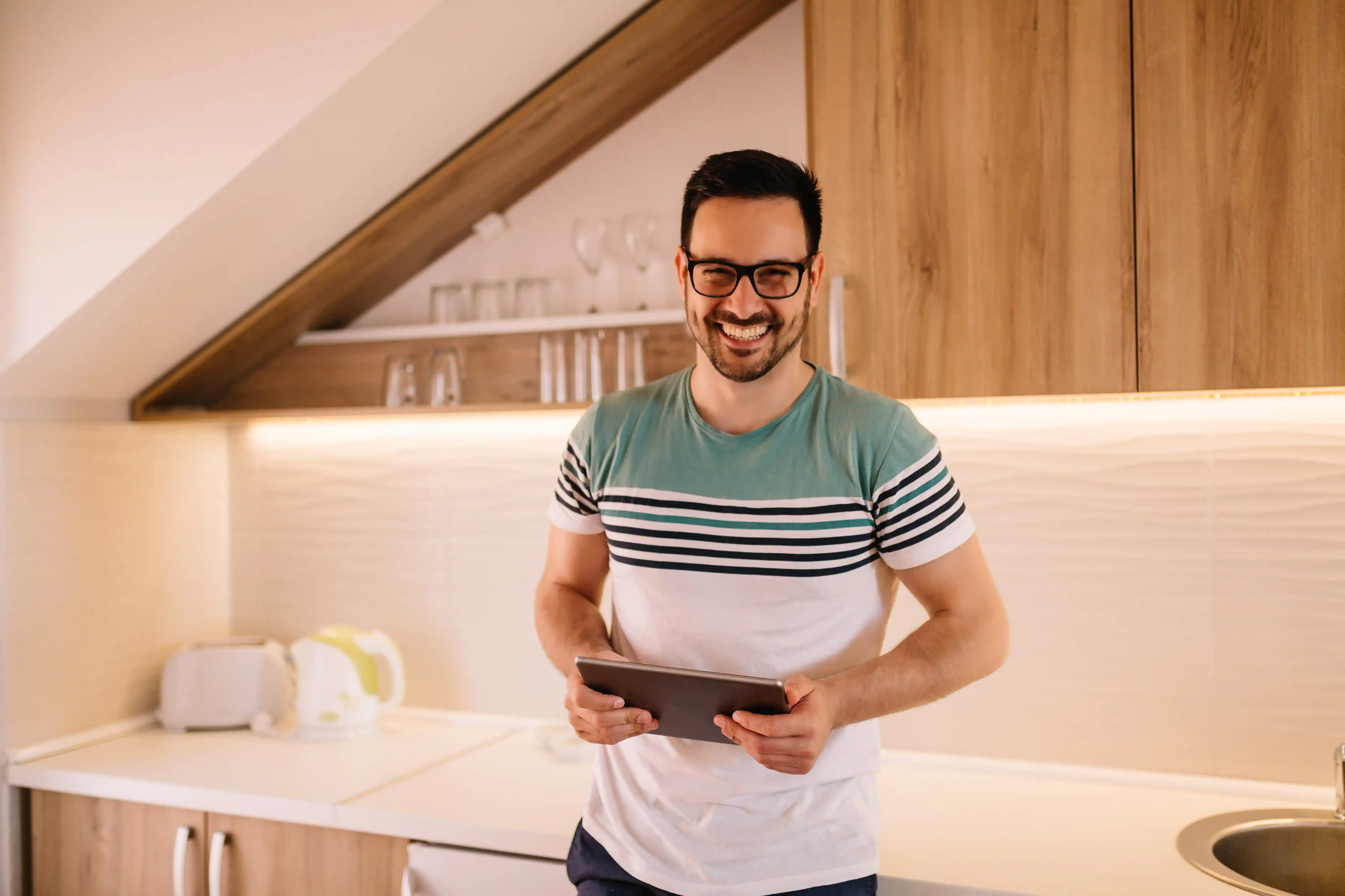Man with tablet in modern kitchen under sloping roof
