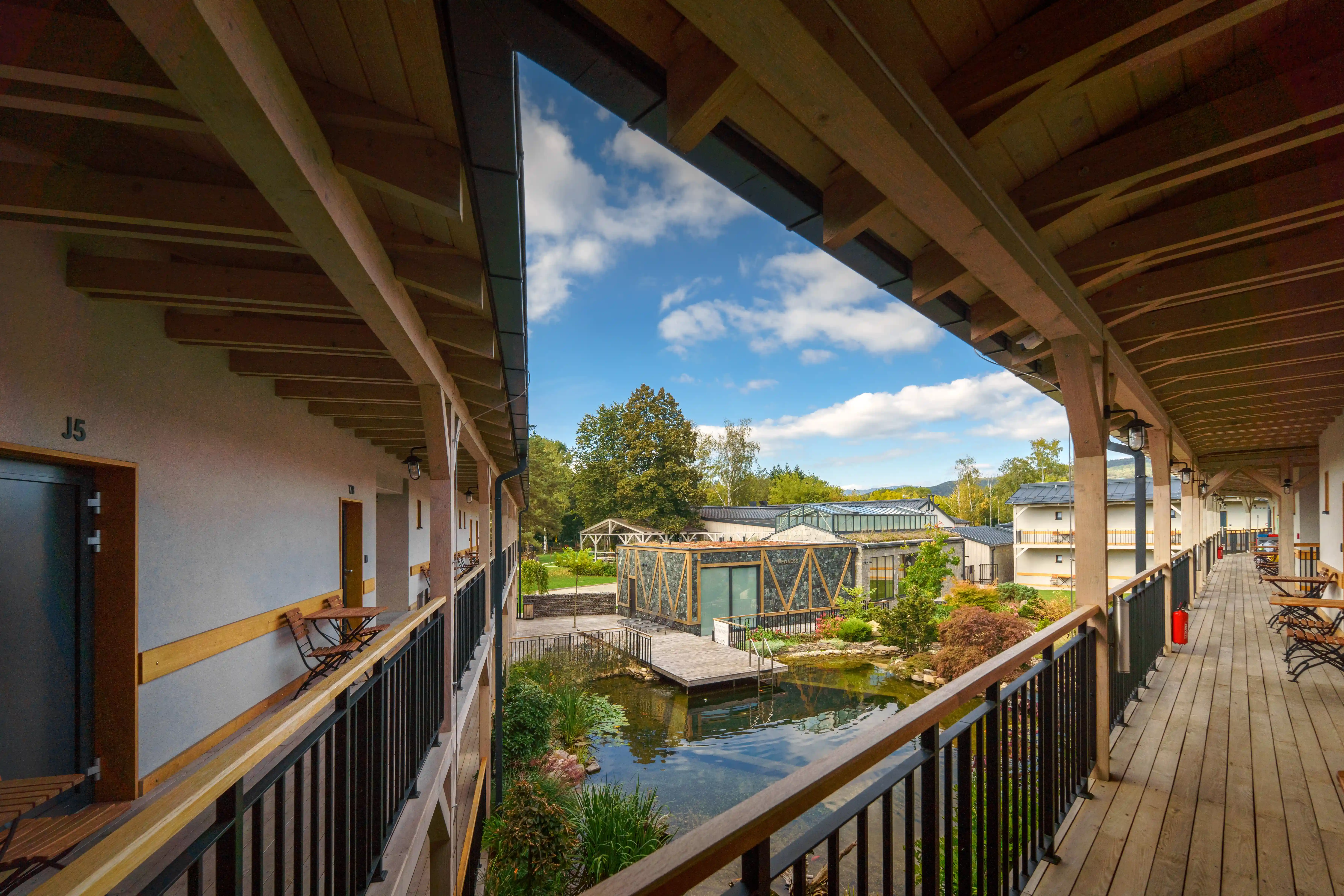 View of hotel complex with wooden balconies and pond