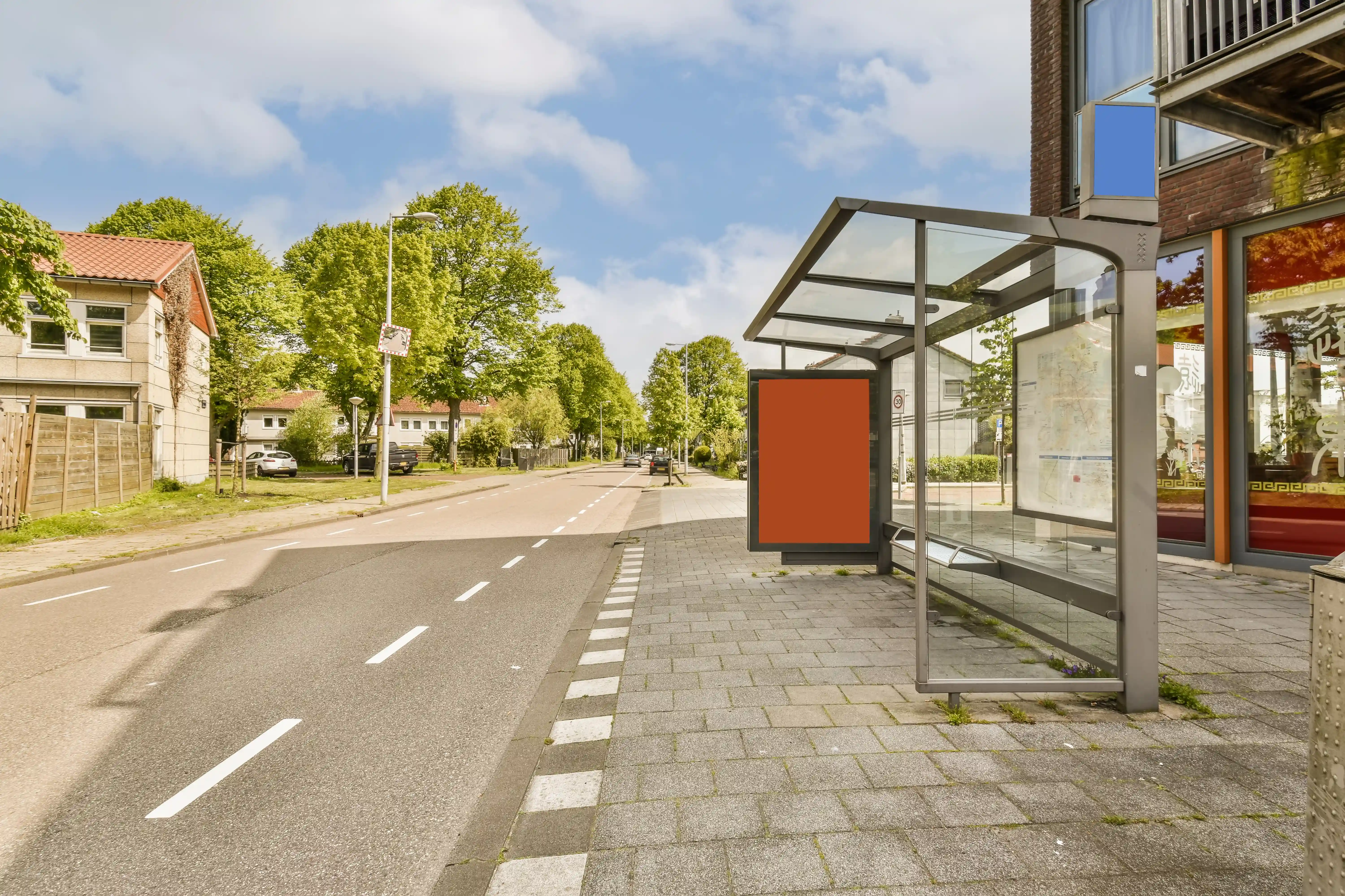 Bus stop with glass shelter and ad panel on a quiet street