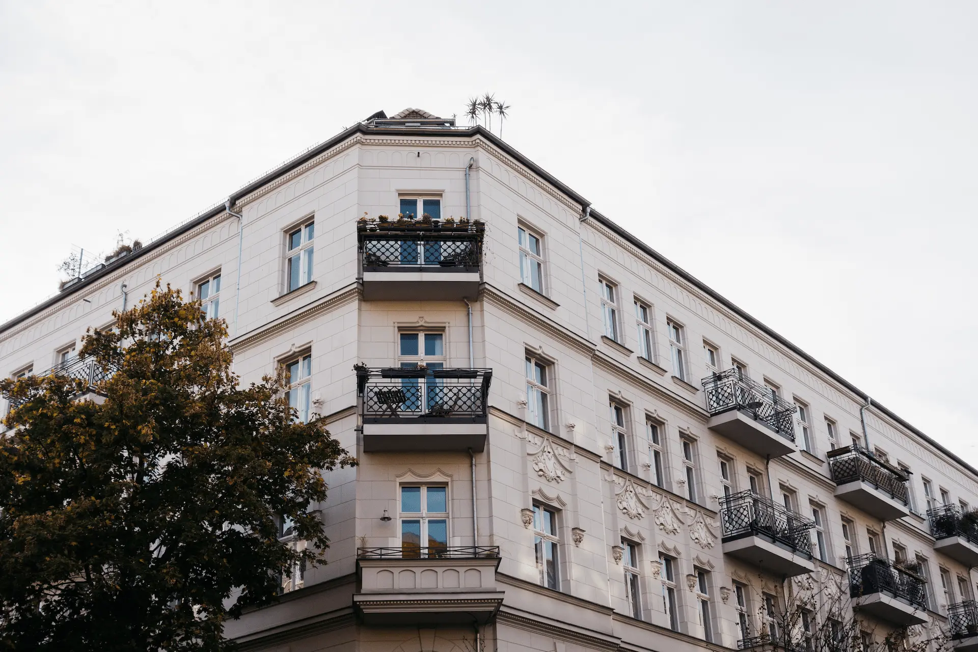 Facade of a multi-family residential building with balconies in an urban setting.