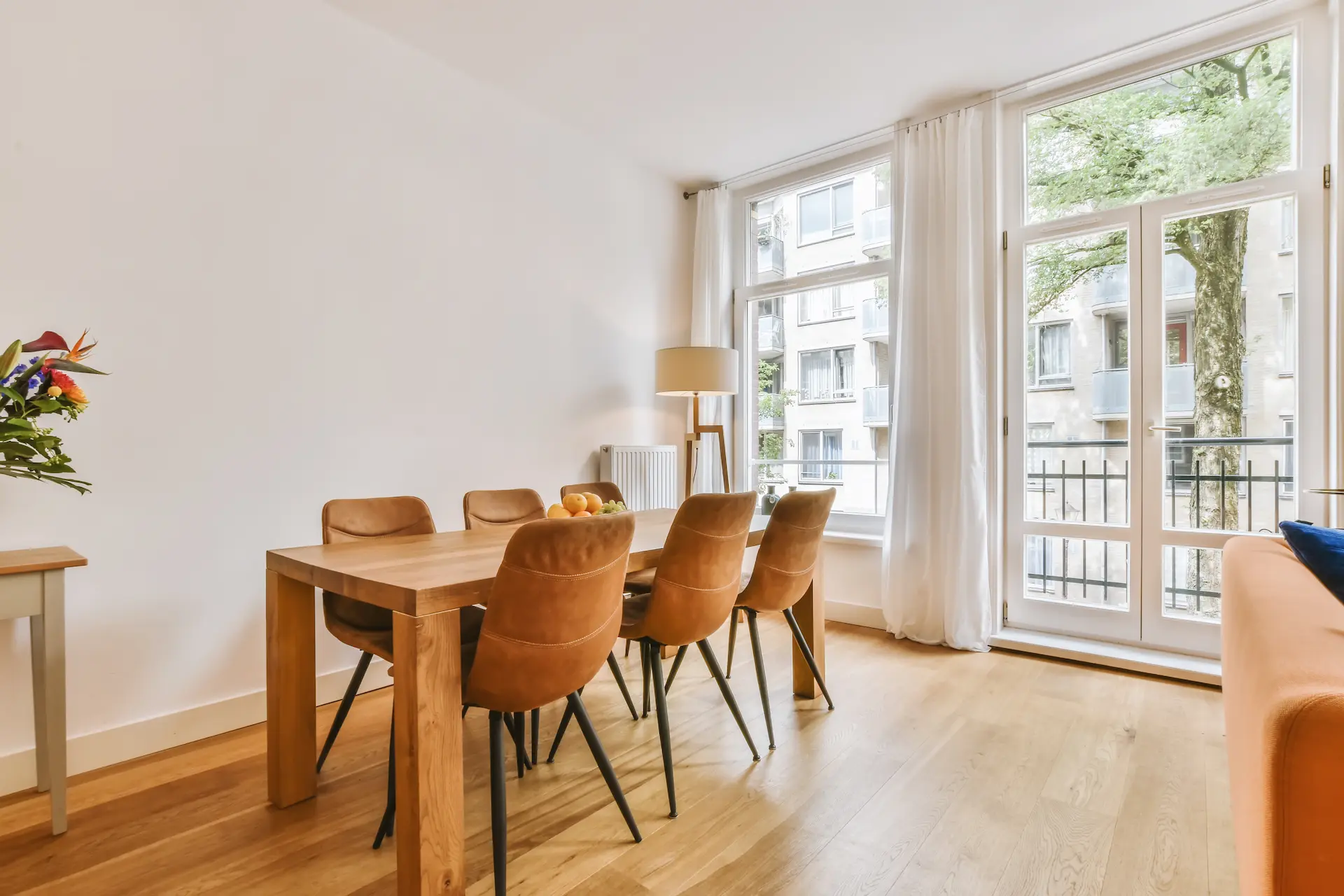 Bright dining room with wooden table, brown chairs, and large windows.