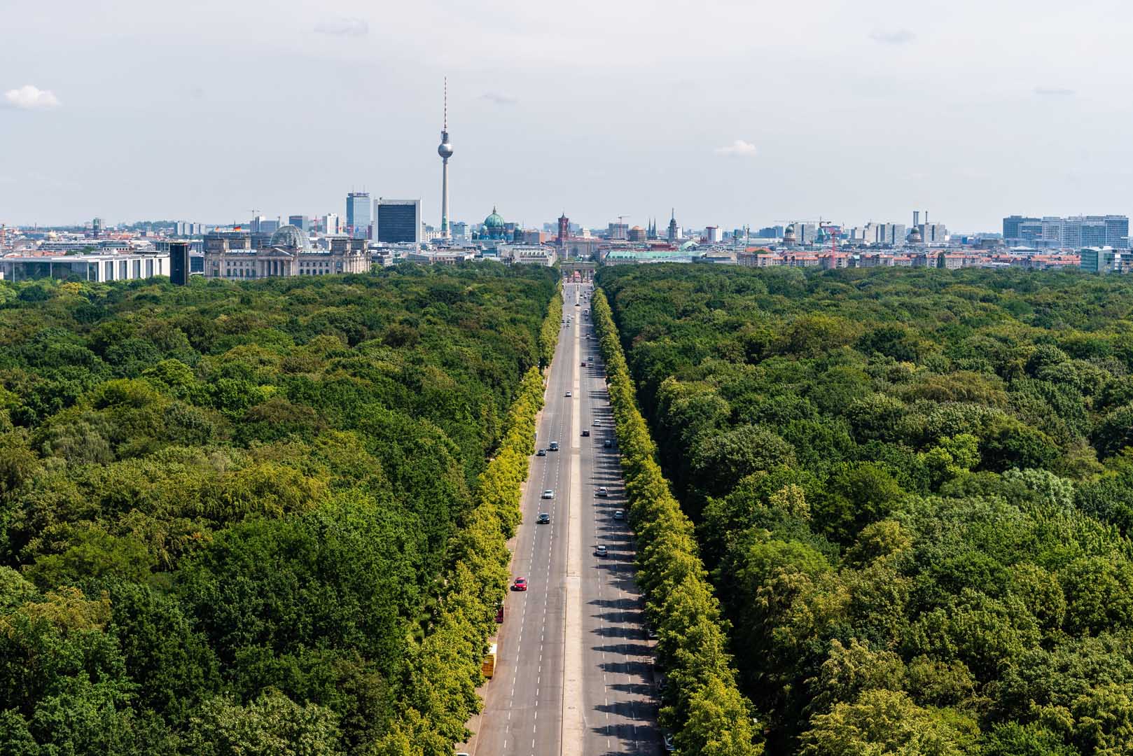 View of Straße des 17. Juni through Tiergarten in Berlin with TV Tower in the background.