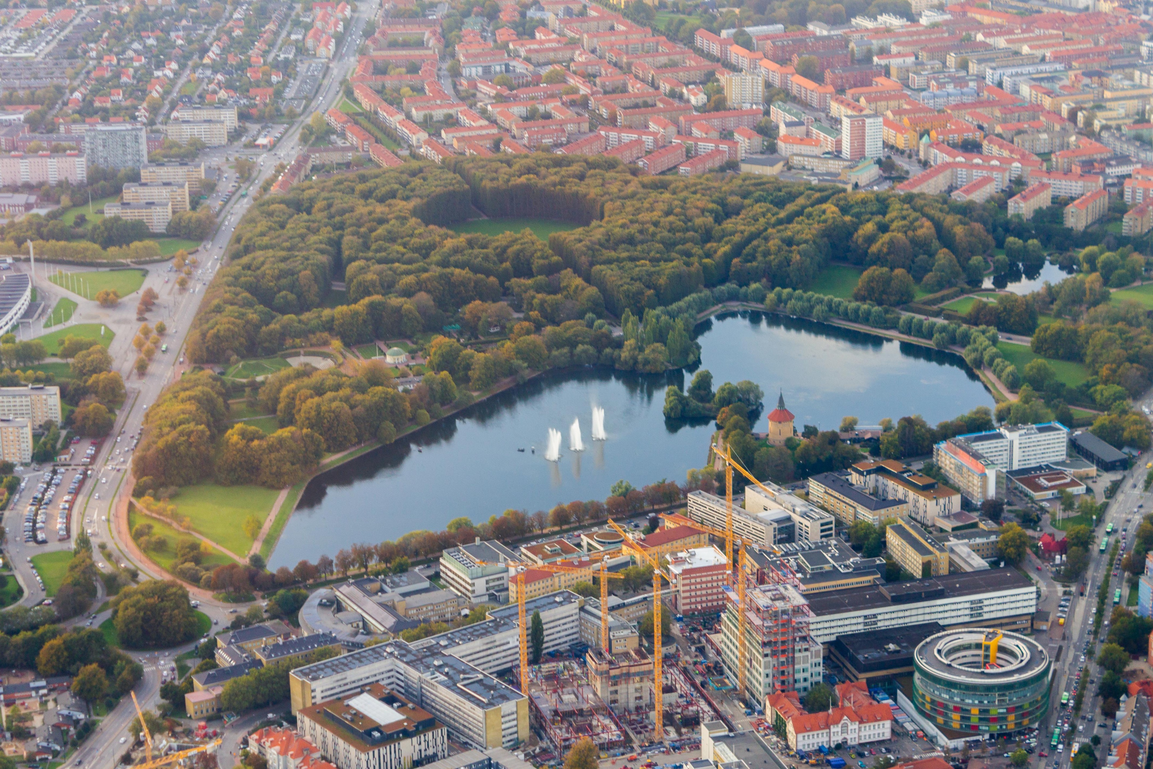 Aerial view of Berlin with a large park, lake with fountains, and surrounding residential buildings.