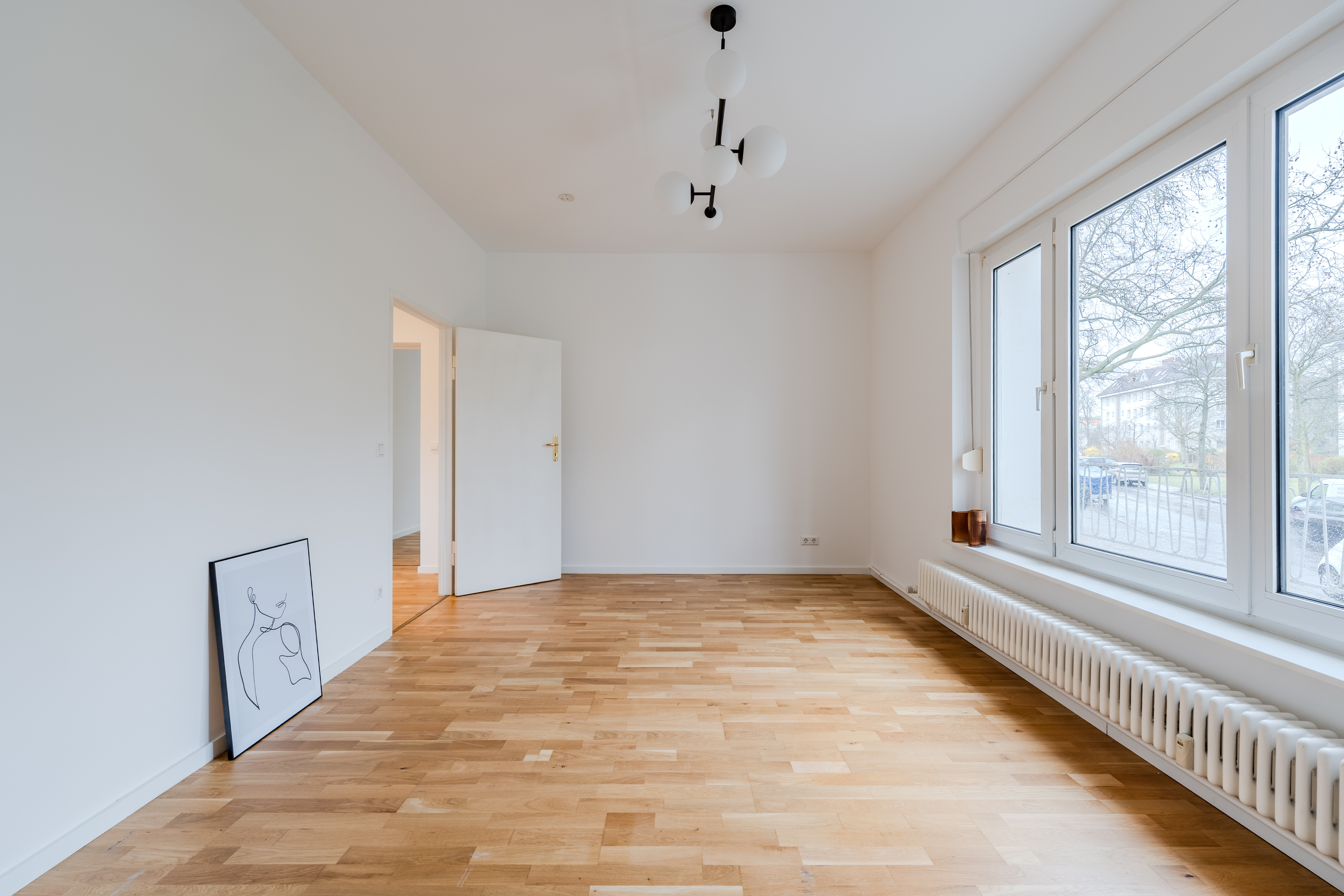 Leerer heller Wohnraum mit Parkettboden und großen Fenstern in Berlin – bezugsfertige provisionsfreie Wohnung
