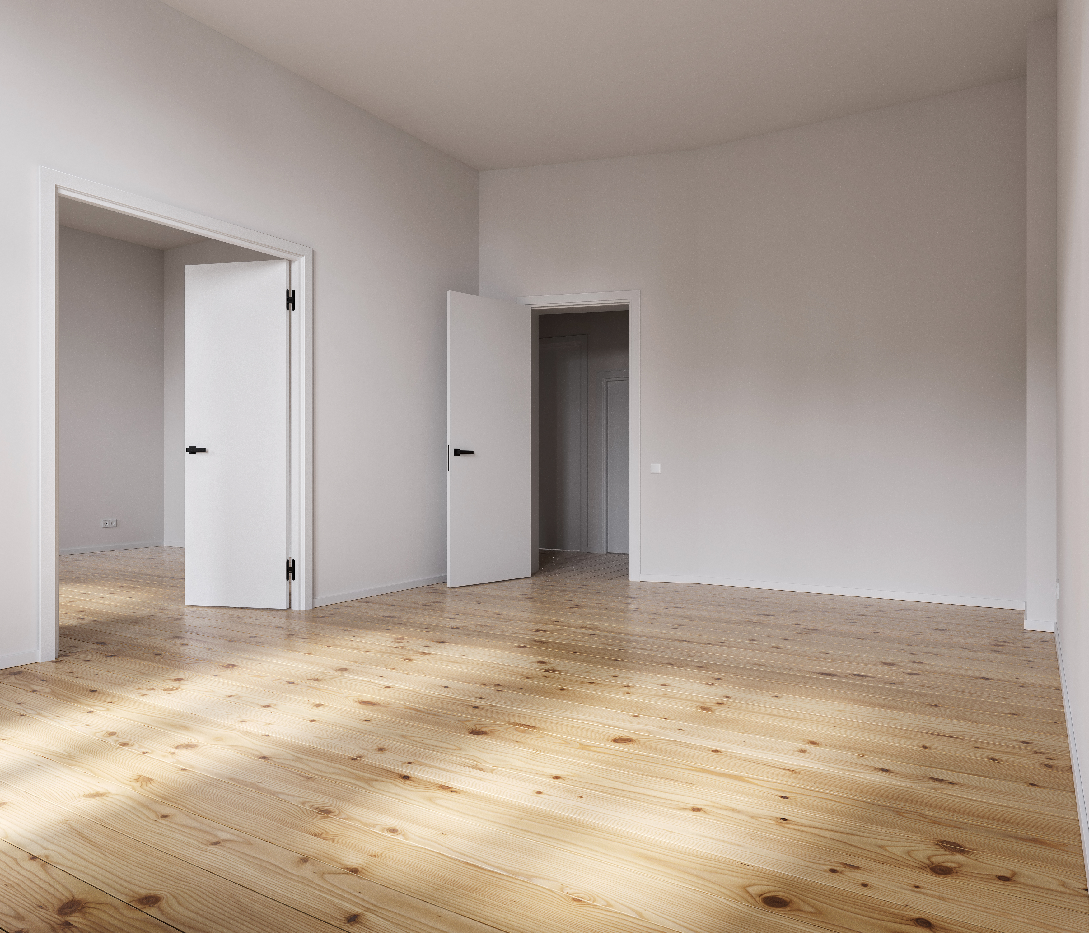 Leeres helles Zimmer mit Holzdielen und weißen Türen – renovierte Wohnung bezugsfertig