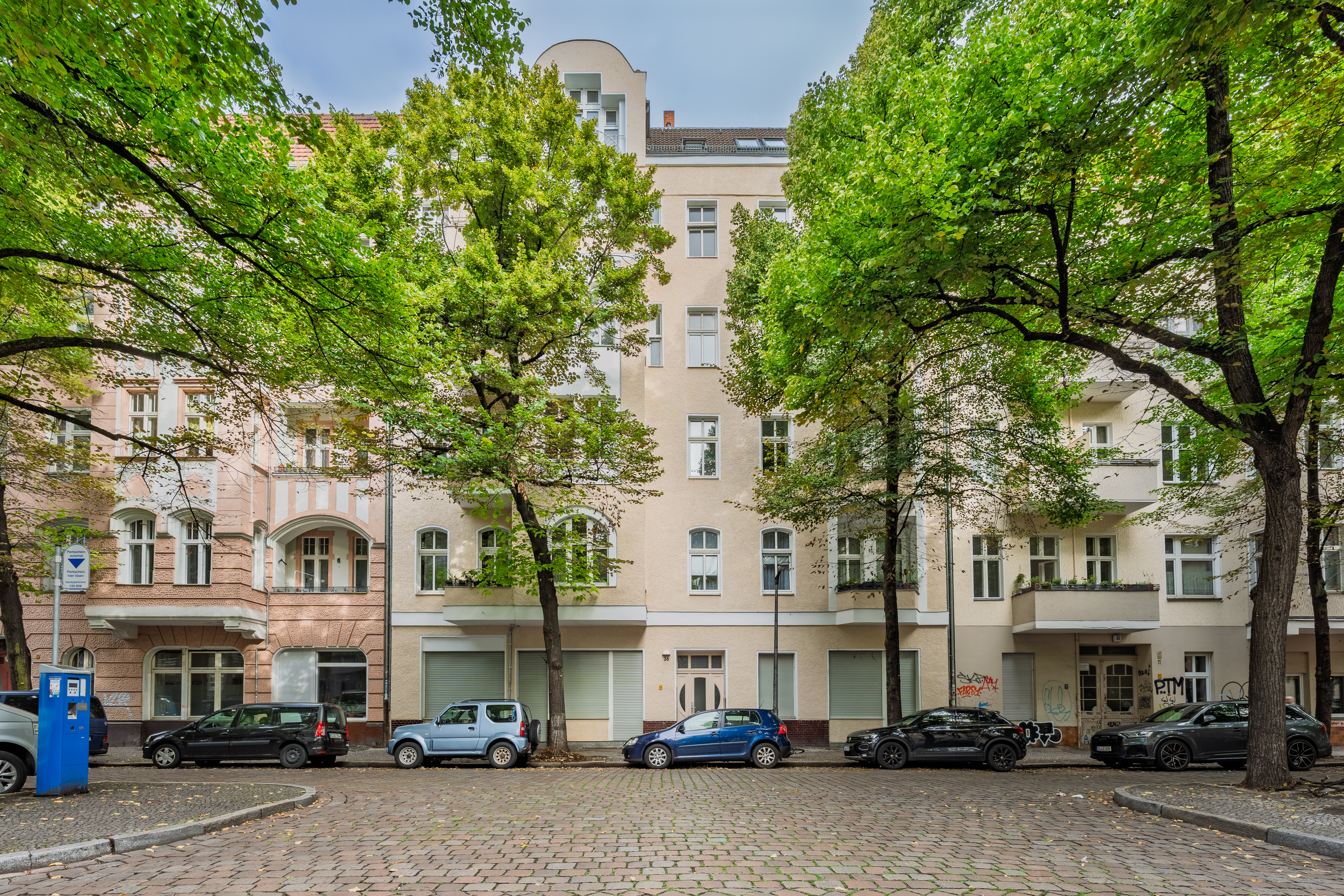 Historic apartment building with trees and parked cars