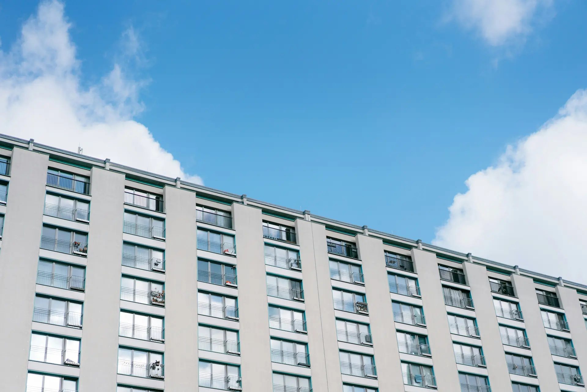 Multi-story apartment building with many balconies under a blue sky.