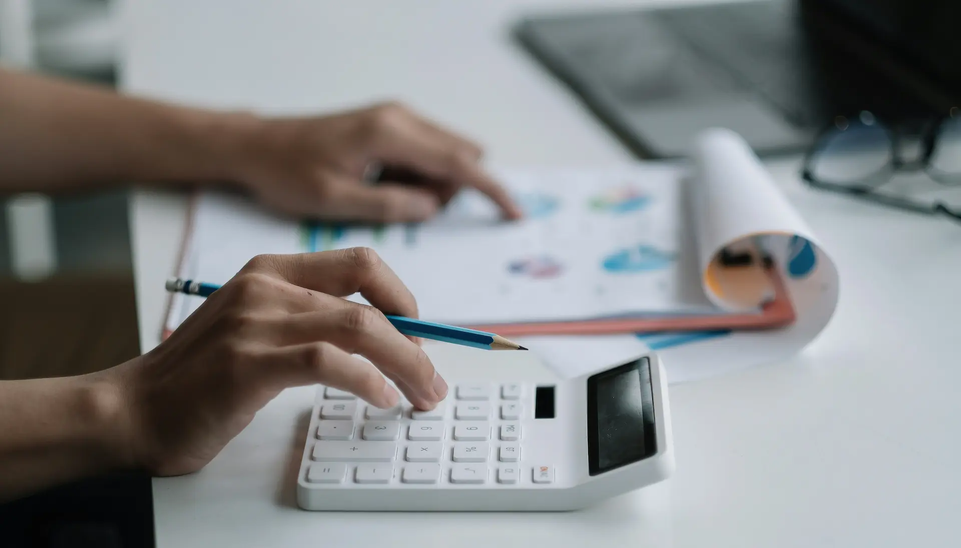 Person using a calculator while reviewing financial documents.