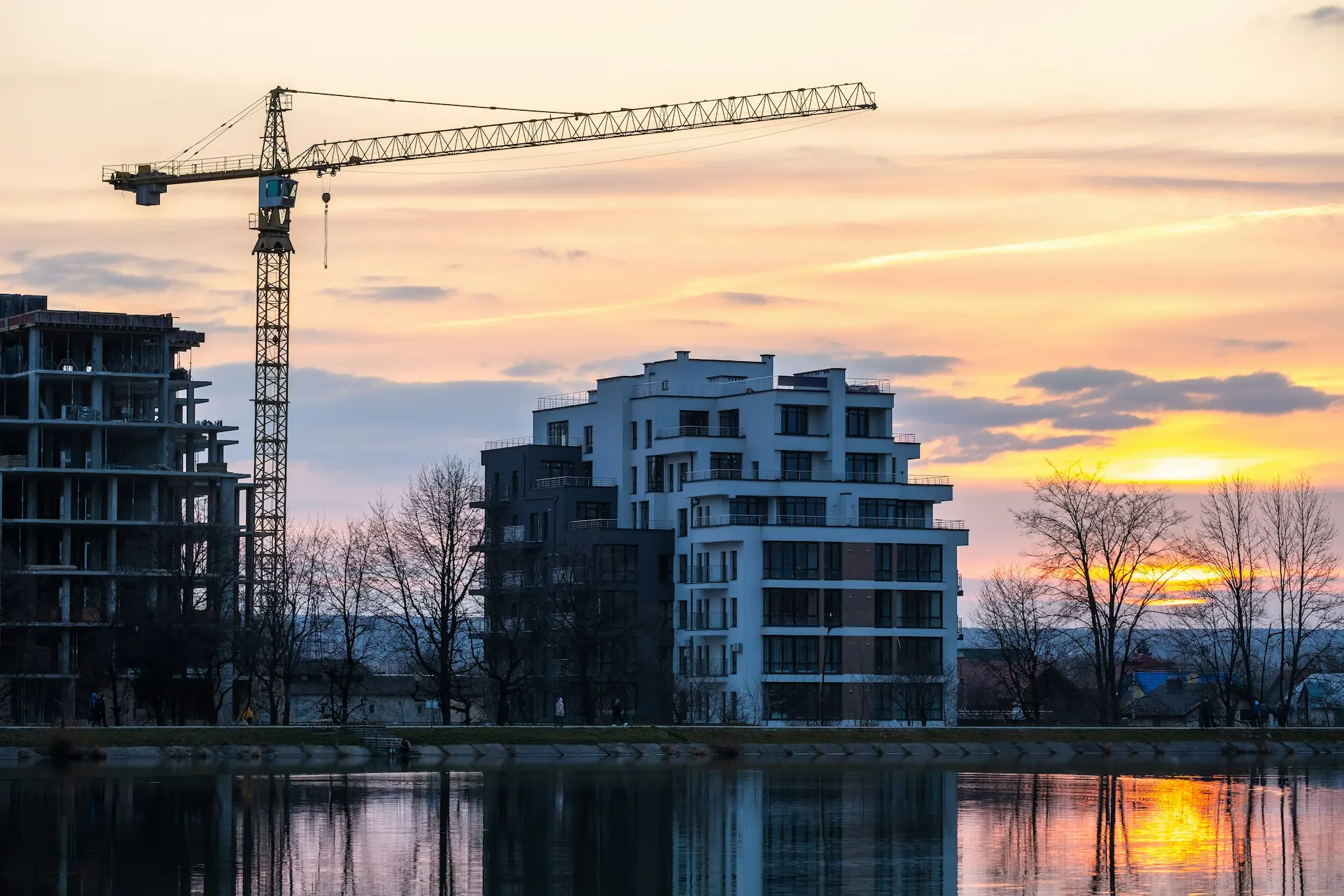  Construction site with crane next to modern apartments by the water at sunset