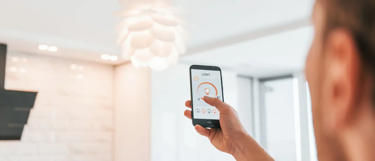 Mann reguliert smartes Lichtsystem per Smartphone zur Erhöhung von Komfort und Sicherheit im Smart Home