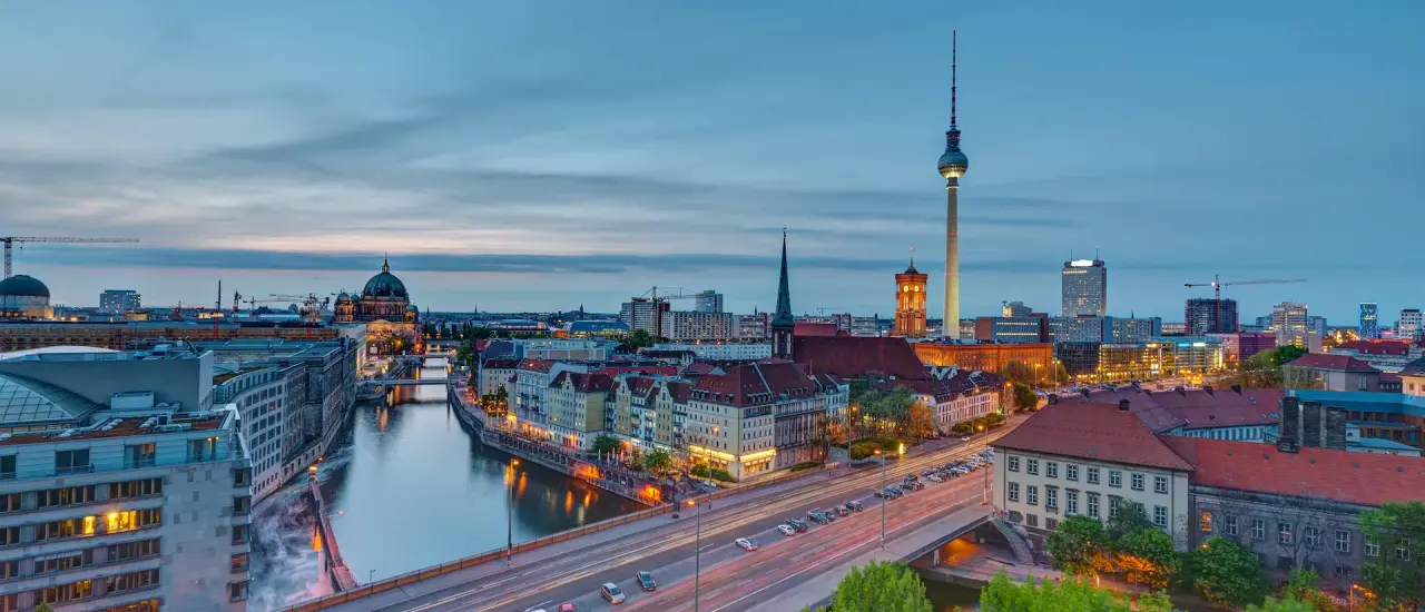 Panorama von Berlin mit Fernsehturm, Spree und historischen Gebäuden bei Abenddämmerung.