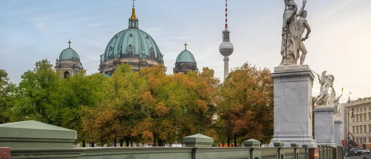 Symbolfoto: Hände beschützen ein kleines Modellhaus, daneben eine Waage und ein Richterhammer.