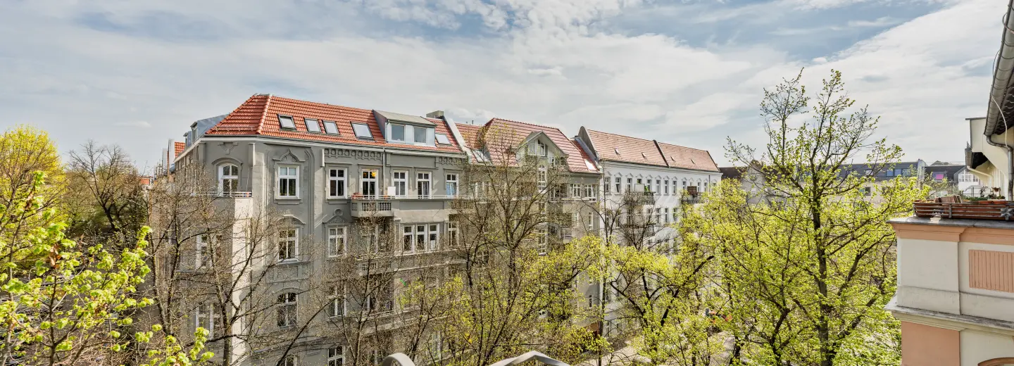 Ausblick vom Balkon auf Altbauten und Bäume