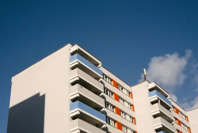 Modernes Wohngebäude mit weißer Fassade und orangefarbenen Akzenten in Berlin – Neubau Eigentumswohnungen