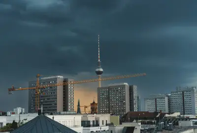 Stadtansicht mit Kran und Fernsehturm vor dunklen Gewitterwolken