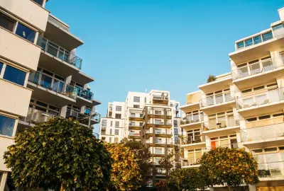 Moderne Wohnanlage mit Balkonen, Bäumen und blauem Himmel