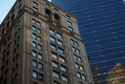Froschperspektive auf historisches Backsteingebäude und modernes Glasfassaden-Hochhaus in der Innenstadt