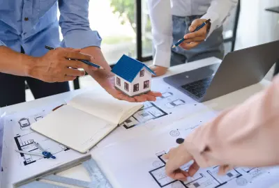 Beratung zur Hausplanung mit Modellhaus und Bauplänen.