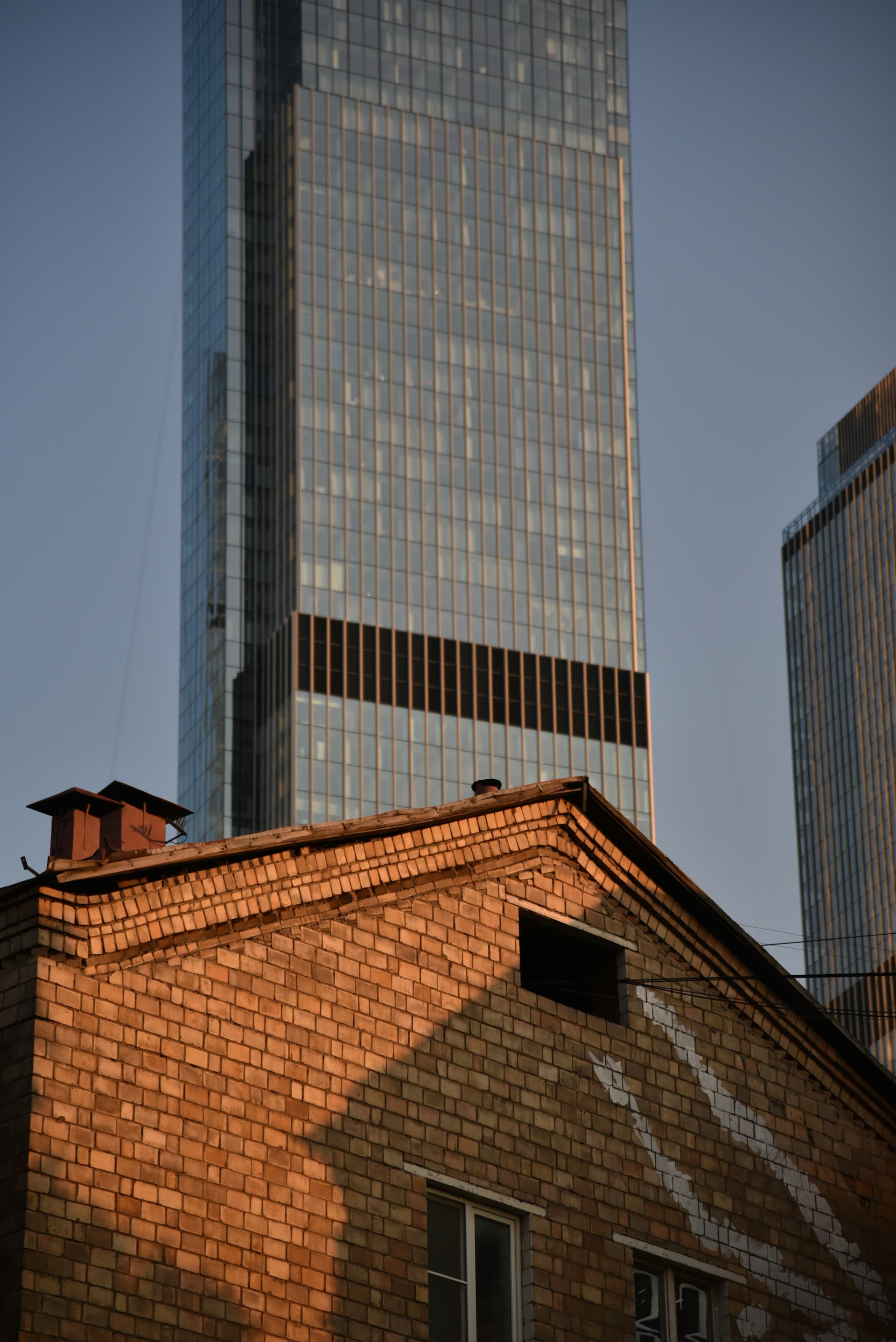 Contrast between old brick building and modern glass skyscraper in the city skyline