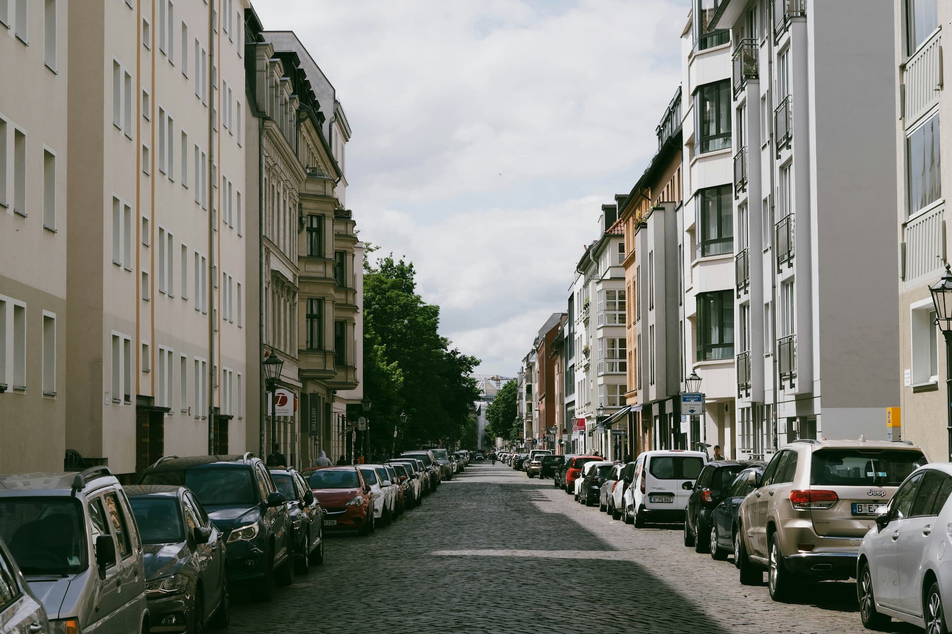 Berliner Kopfsteinpflaster-Wohnstraße mit geparkten Autos und Altbauten – städtische Wohnlage