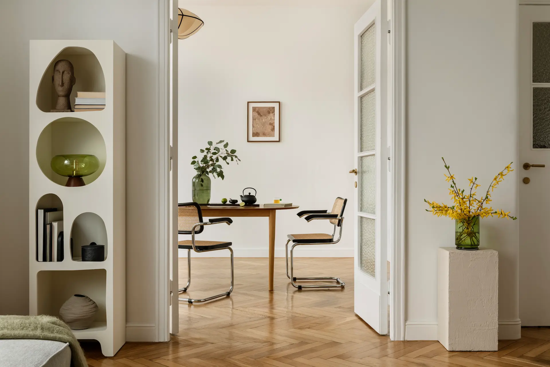 Bright minimalist dining area with wooden floor, table, chairs, and decor.