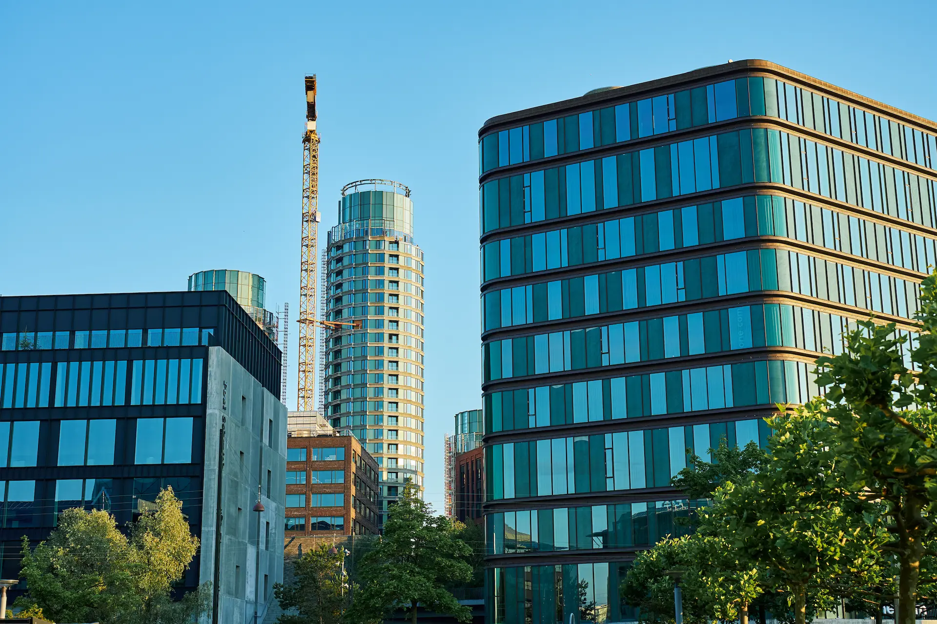Modern office buildings with glass facades and a construction crane in the city.