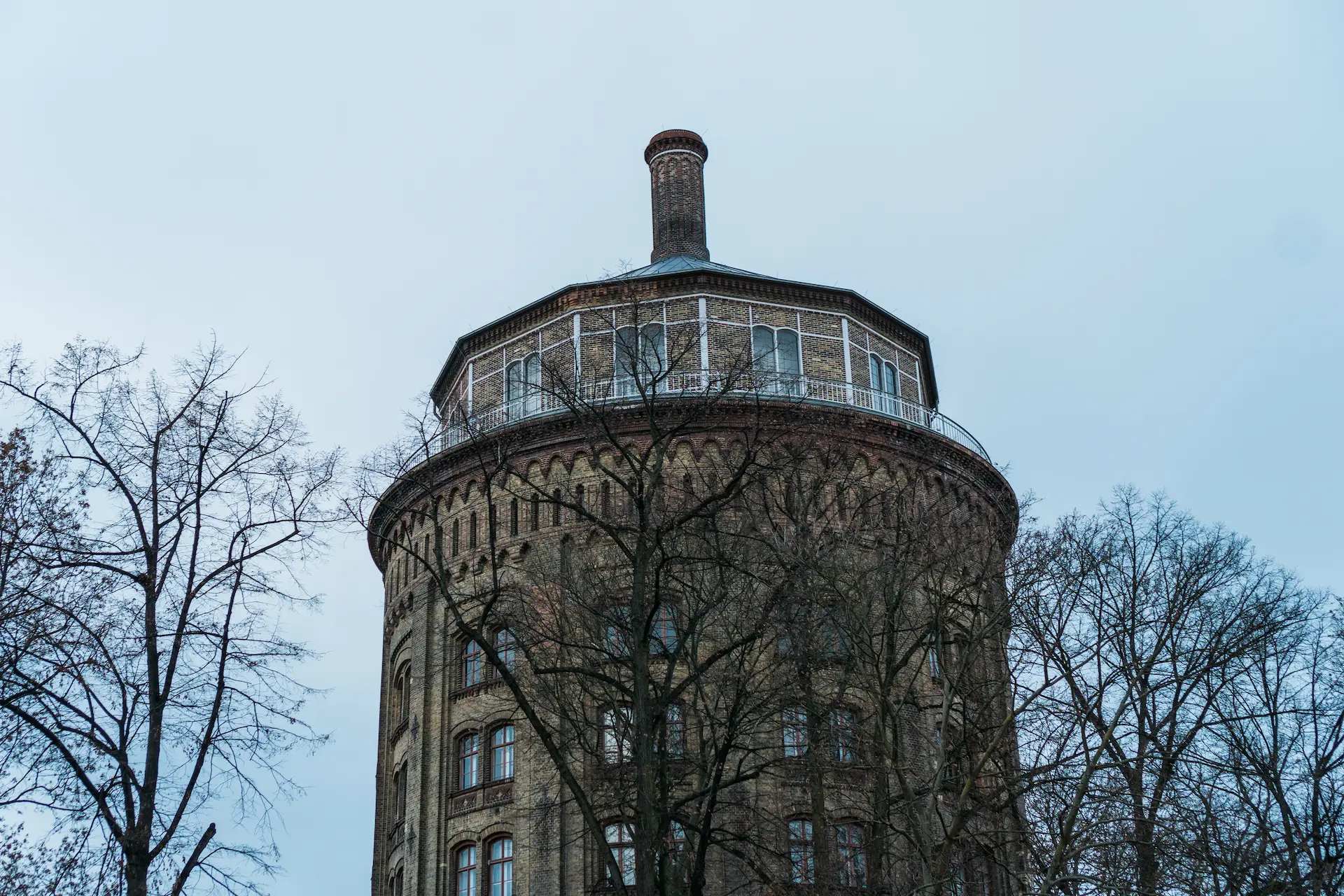 Round historic brick building with a chimney, surrounded by leafless trees.