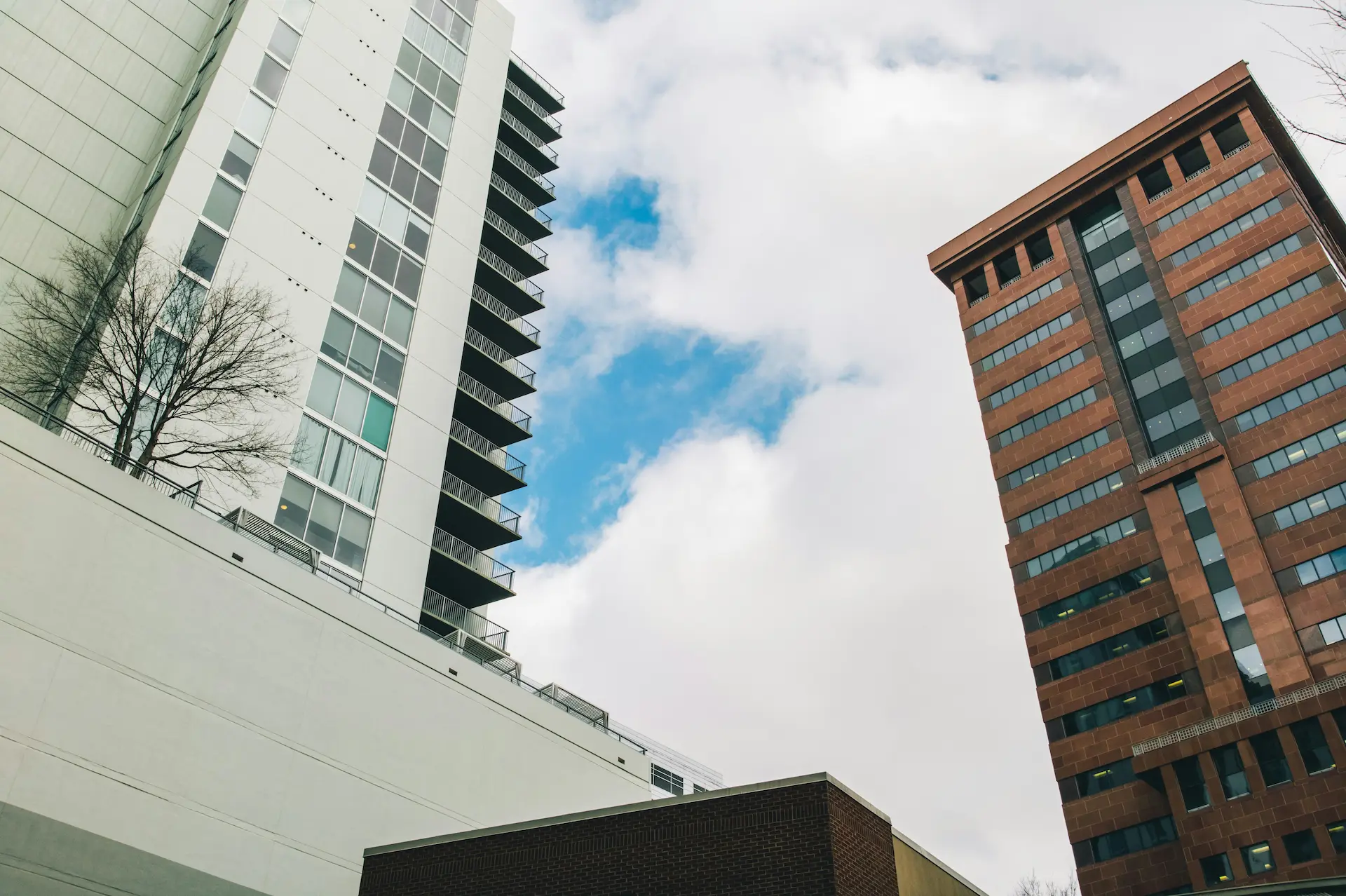  Upward view between modern high-rise buildings under a cloudy sky