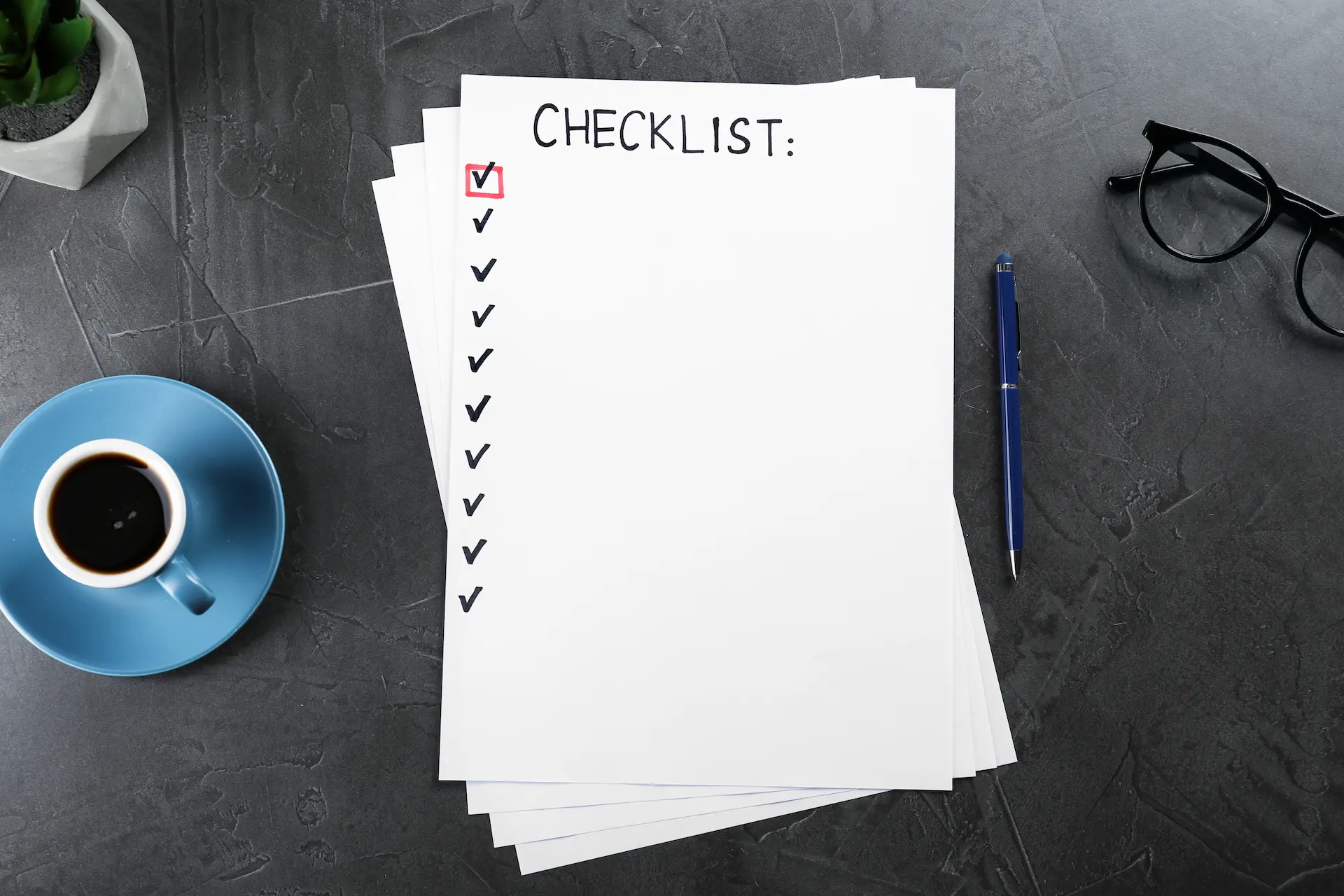 Checklist on a desk with pen and coffee cup.