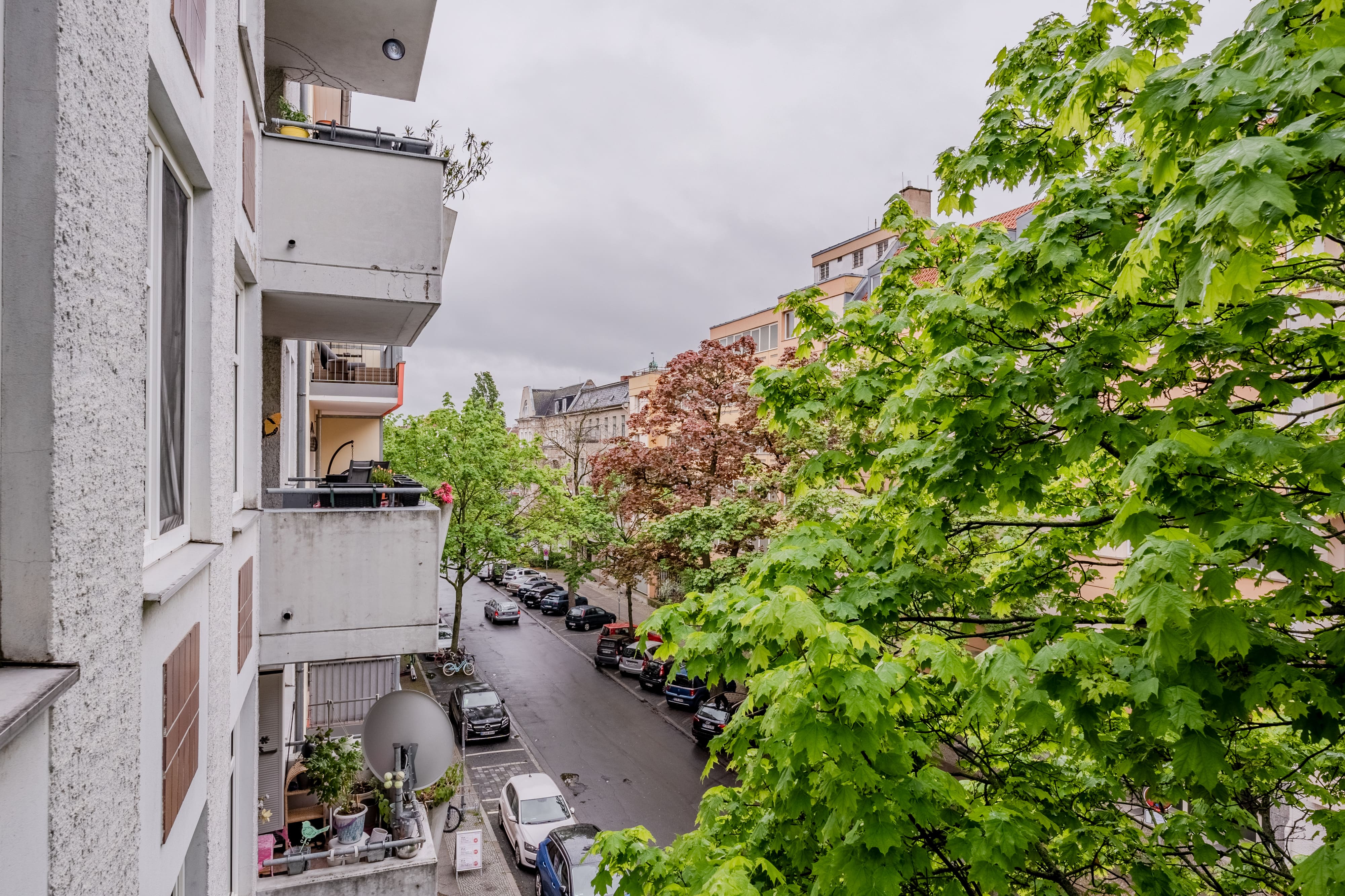Ruhige Wohnstraße mit Balkonen und grünen Bäumen in Berlin