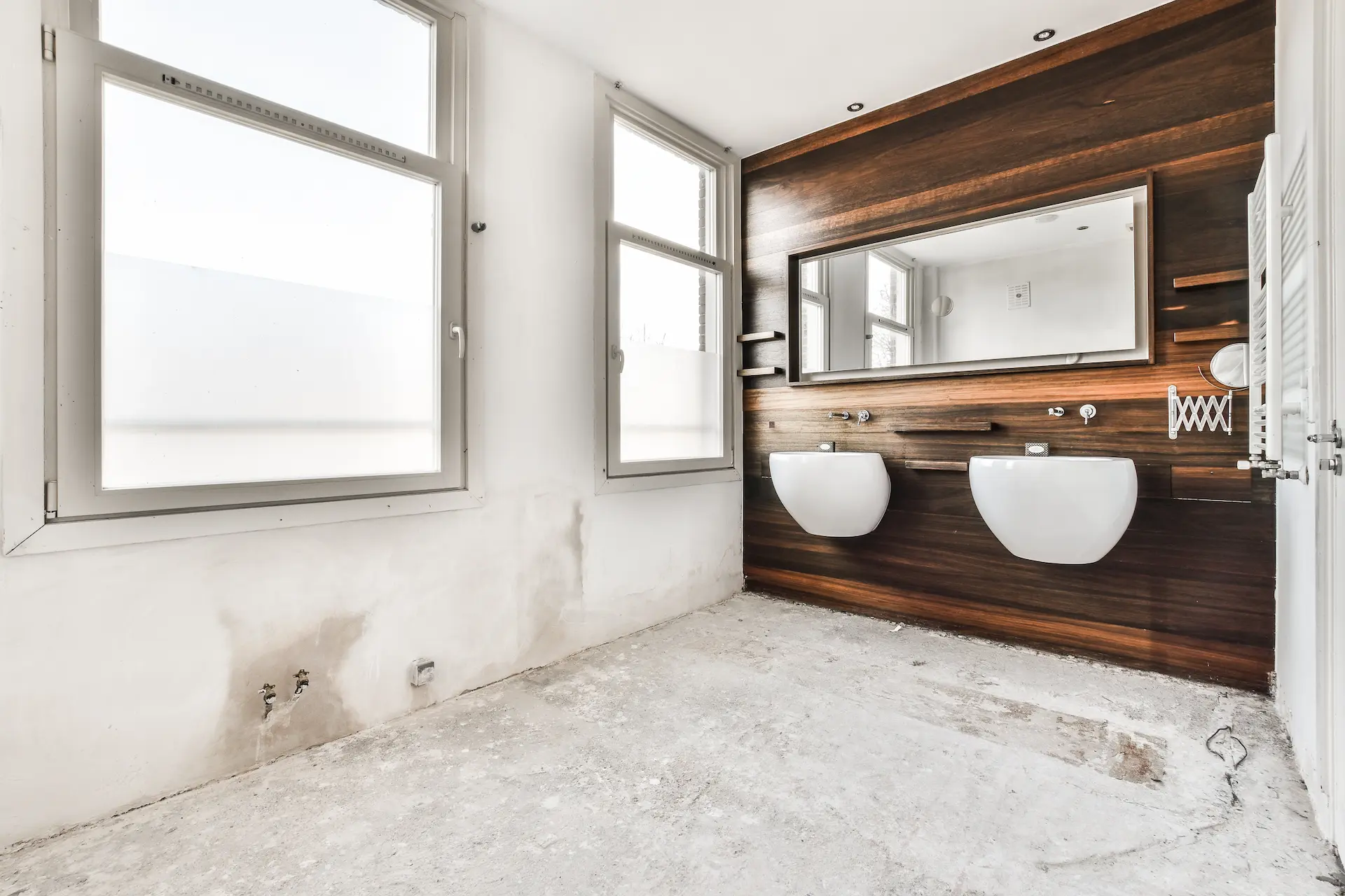 Modernes Bad im Rohbau mit Doppelwaschbecken und Holzrückwand