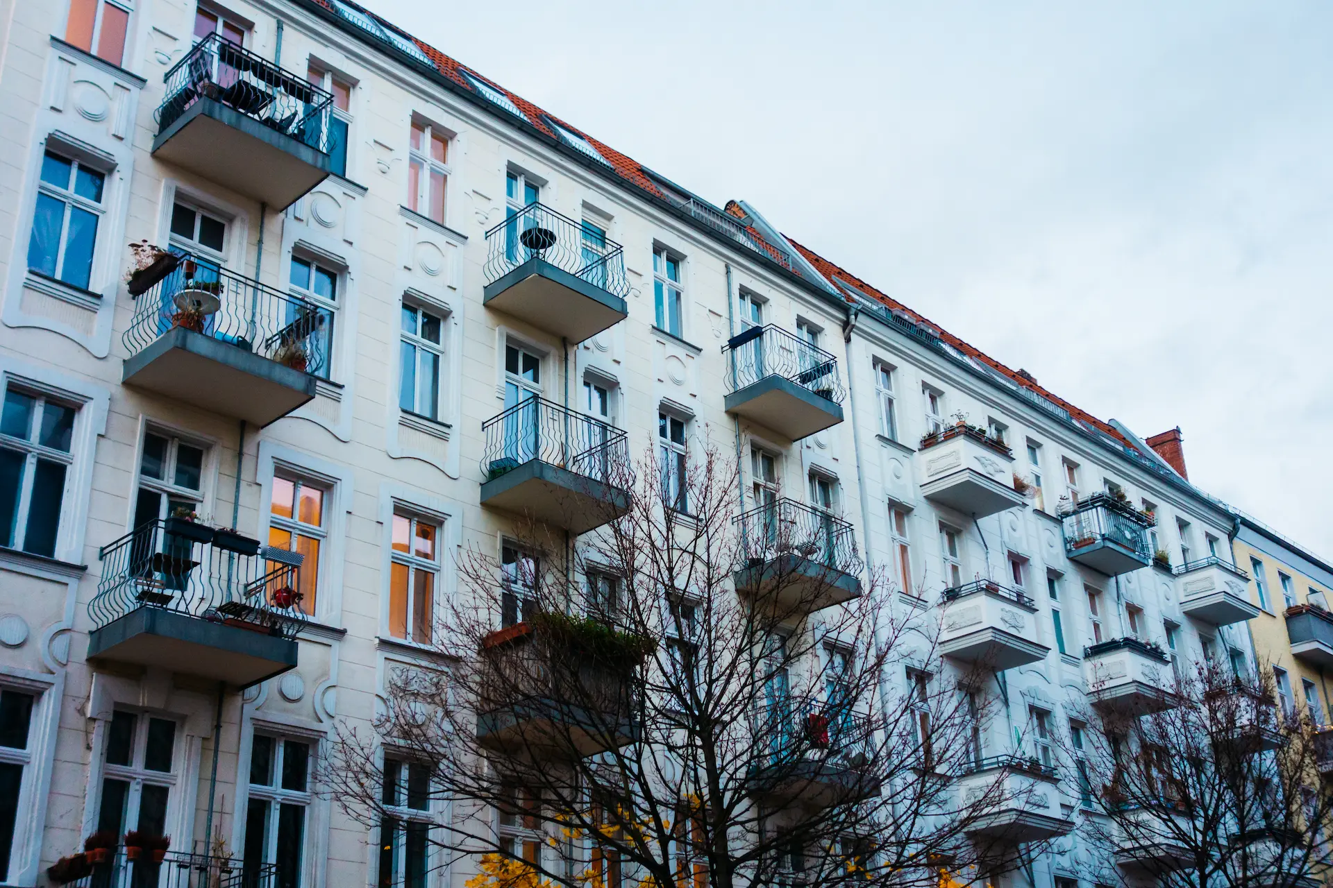 Multi-story historic apartment building with white façade and balconies on a city street.