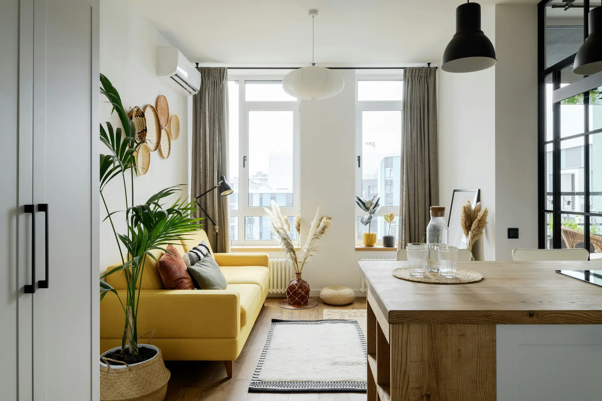 Bright living room with yellow sofa, plants, and large window.